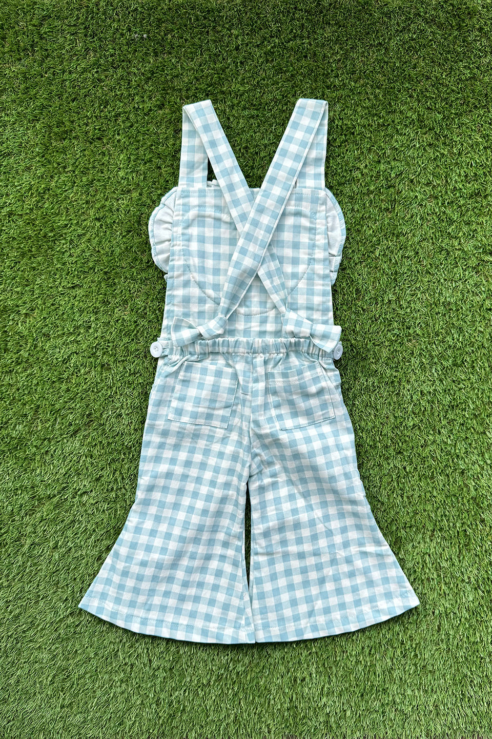 Get ready to fall in love with these Blue Gingham heart shape overalls! Made for little girls, these overalls feature a flared pant leg for added style and comfort. Perfect for any occasion, your little one will look adorable in these playful and unique overalls!. The flare pants add a playful touch to this charming piece. Your little one will surely steal the show in this sweet and stylish outfit. Flat lay back