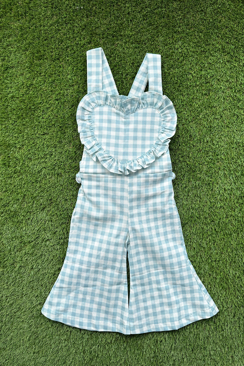 Get ready to fall in love with these Blue Gingham heart shape overalls! Made for little girls, these overalls feature a flared pant leg for added style and comfort. Perfect for any occasion, your little one will look adorable in these playful and unique overalls!. The flare pants add a playful touch to this charming piece. Your little one will surely steal the show in this sweet and stylish outfit. Front  flat lay