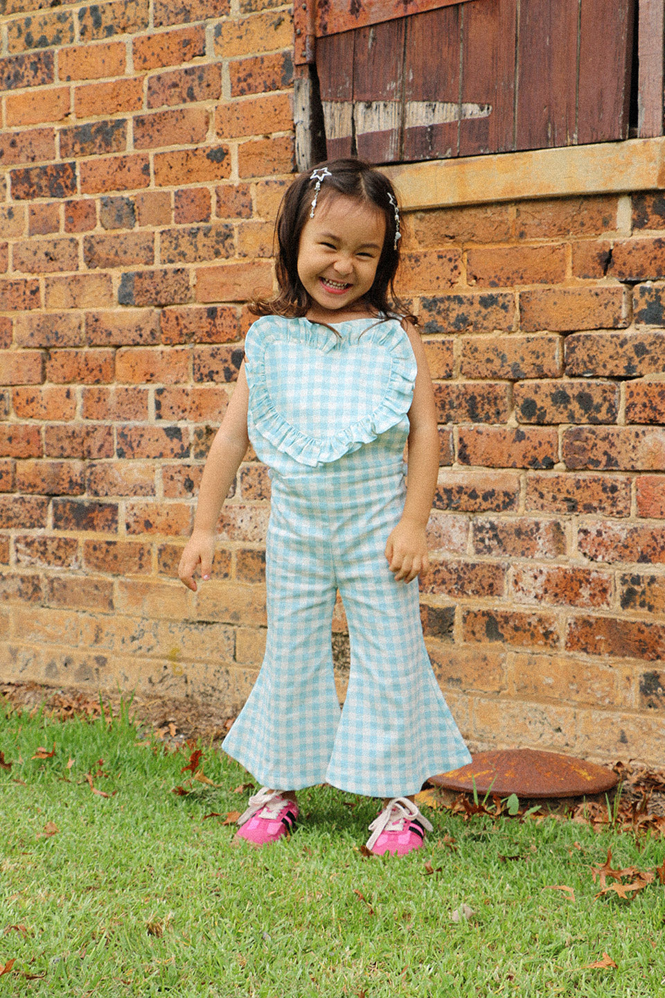 Get ready to fall in love with these Blue Gingham heart shape overalls! Made for little girls, these overalls feature a flared pant leg for added style and comfort. Perfect for any occasion, your little one will look adorable in these playful and unique overalls!. The flare pants add a playful touch to this charming piece. Your little one will surely steal the show in this sweet and stylish outfit. Lifestyle front