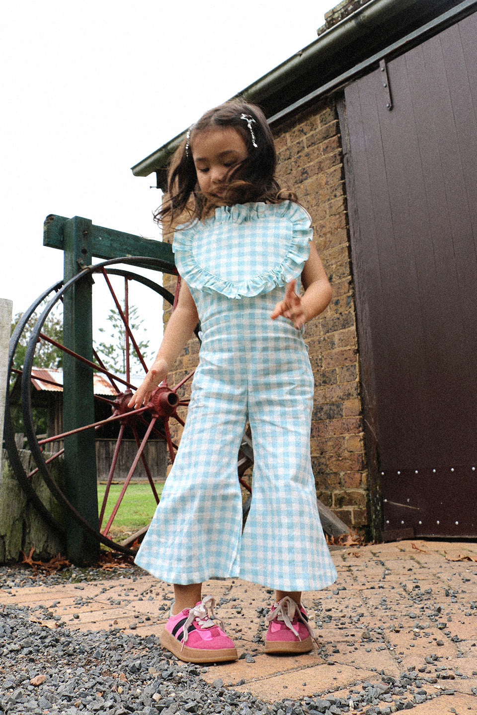 Get ready to fall in love with these Blue Gingham heart shape overalls! Made for little girls, these overalls feature a flared pant leg for added style and comfort. Perfect for any occasion, your little one will look adorable in these playful and unique overalls!. The flare pants add a playful touch to this charming piece. Your little one will surely steal the show in this sweet and stylish outfit. Front lifestyle